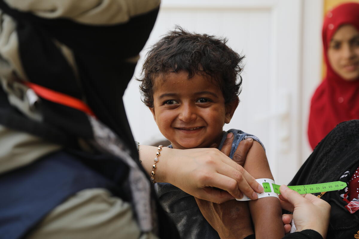 Child being measured for malnutrition with tape around arm.