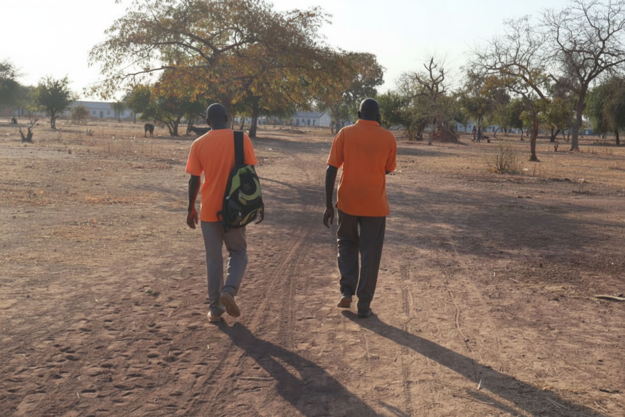 Two people walk together towards buildings in the distance