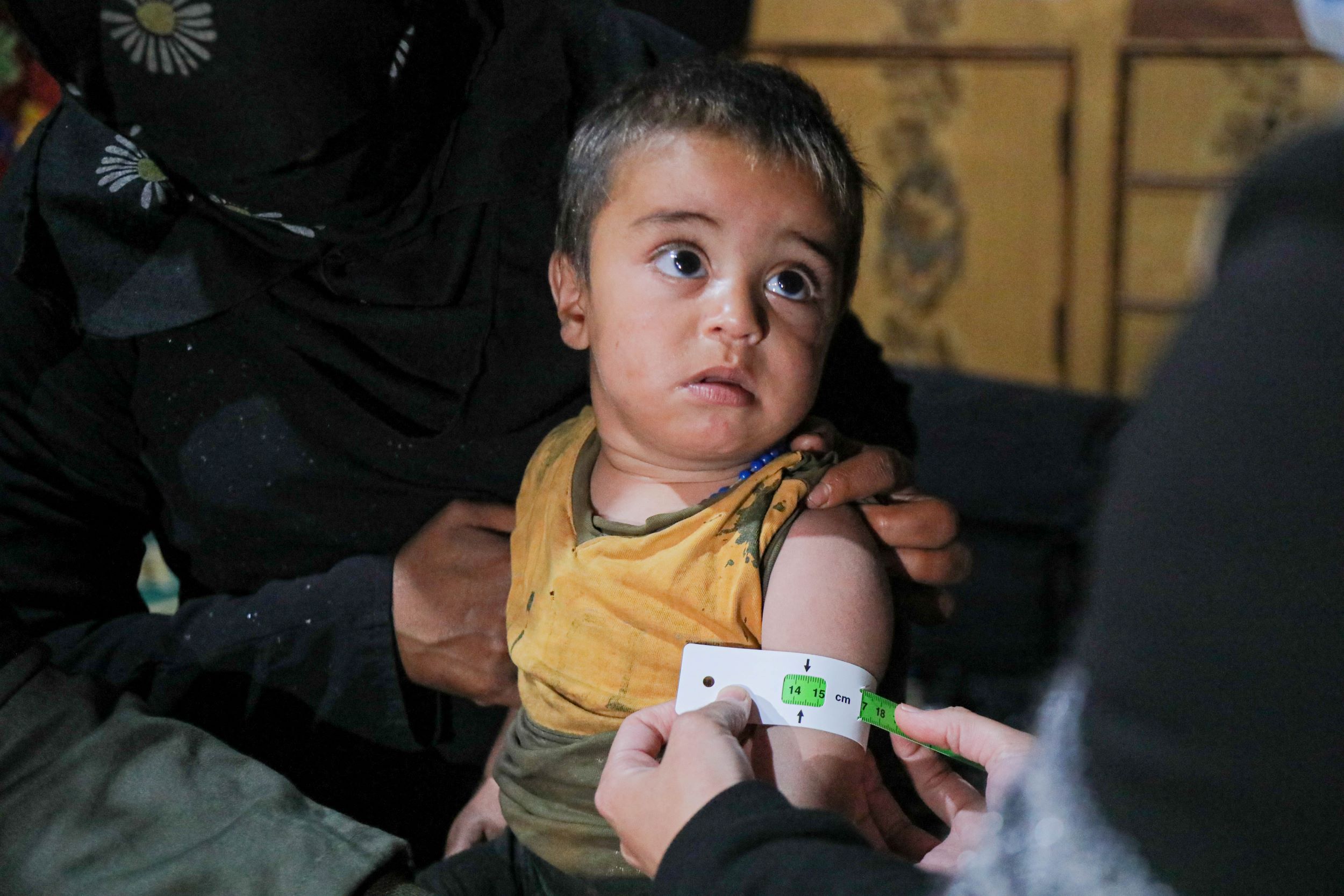 Baby in yellow top being receiving a health check