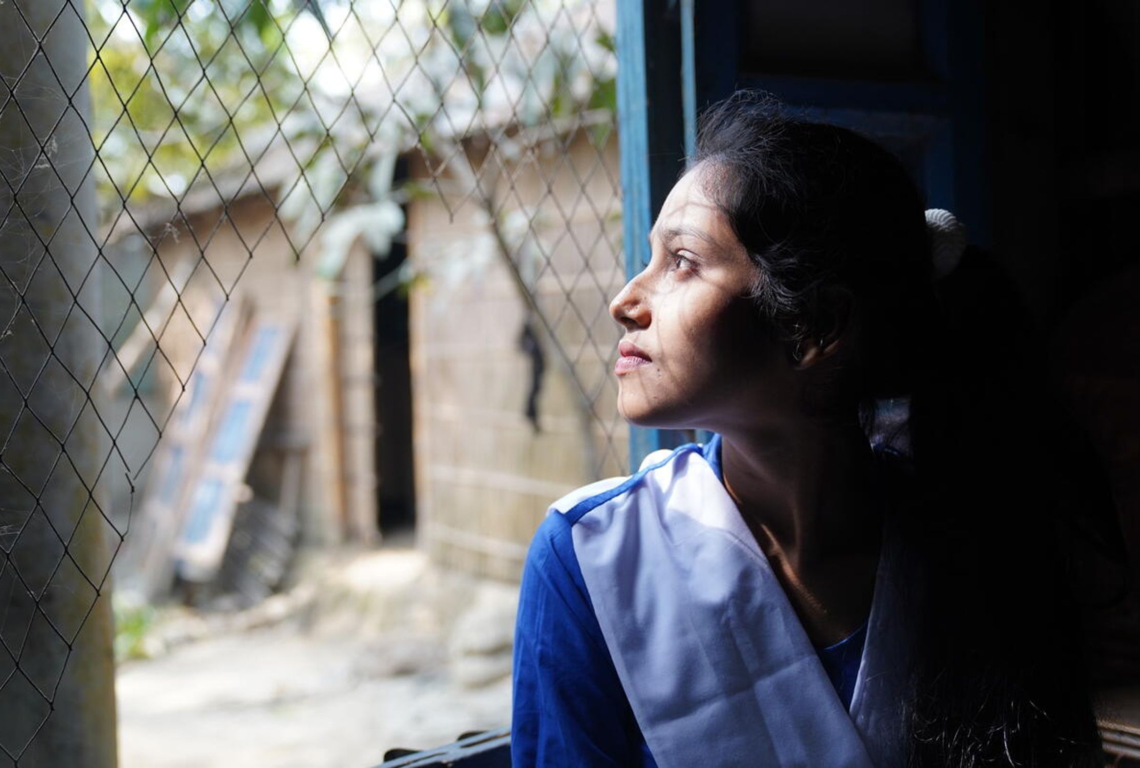 Girl from Bangladesh looks outside through a window
