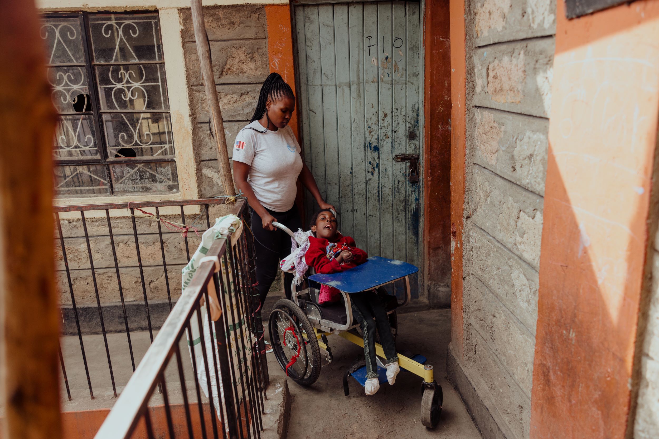 A Kenyan woman pushes her disabled younger sister in her wheelchair