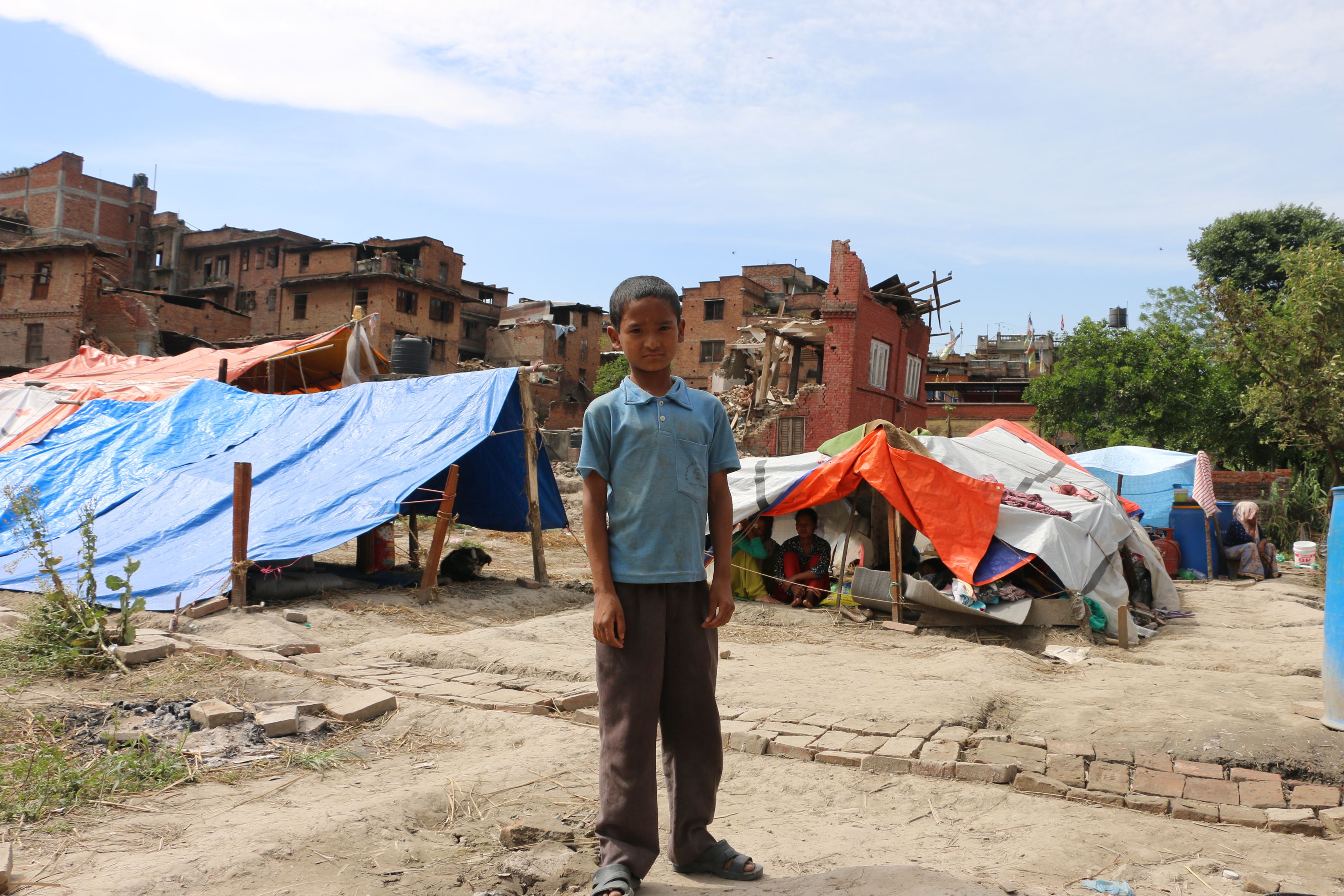 A boy stands in front of makeshift tents in Nepal nearby to where an earthquake hit