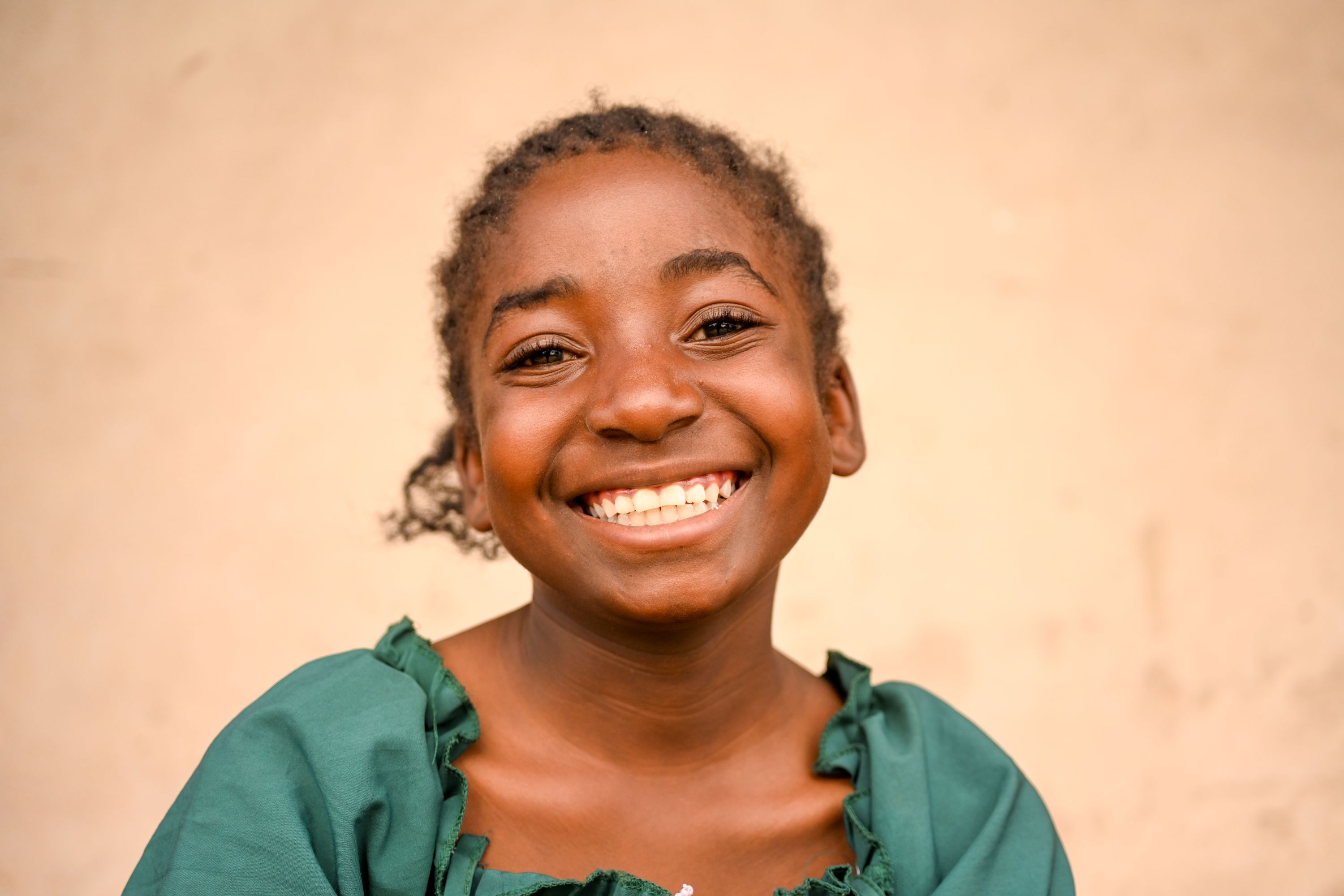 A young boy smiles in field in Kenya