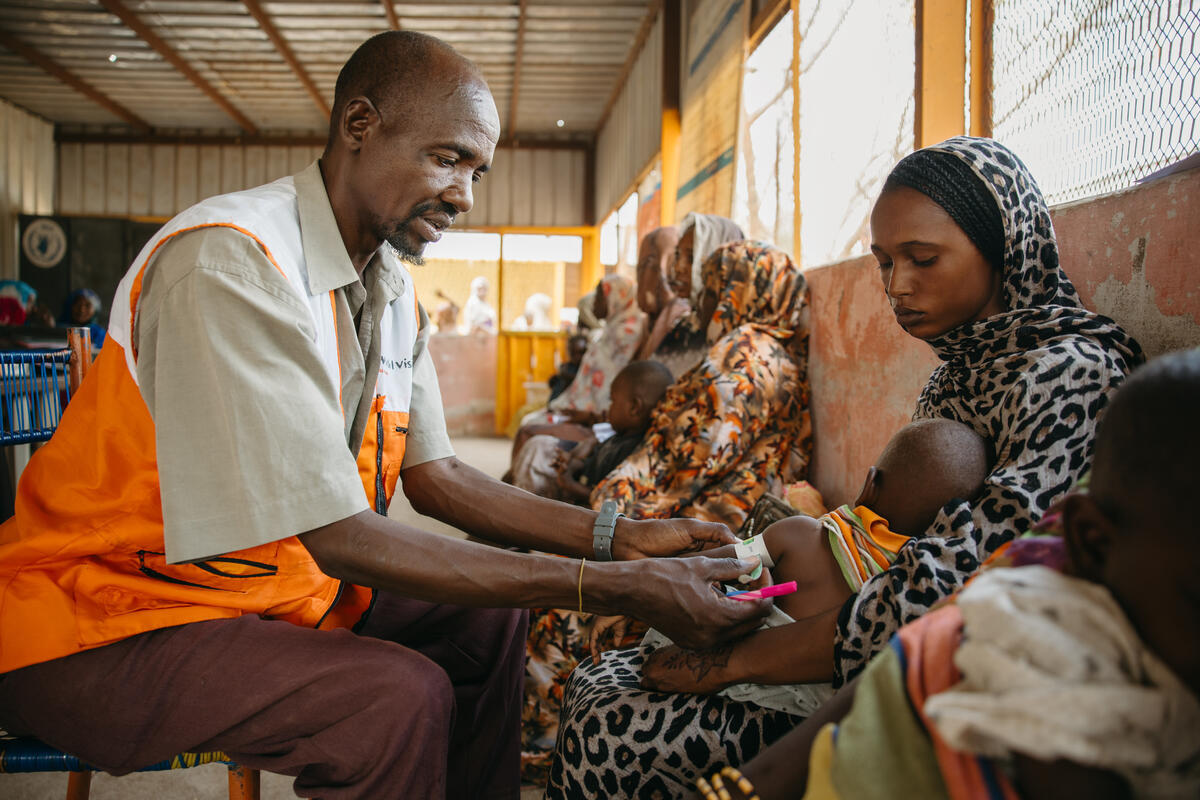 WV staff member checking on a baby whilst held by its Mother.