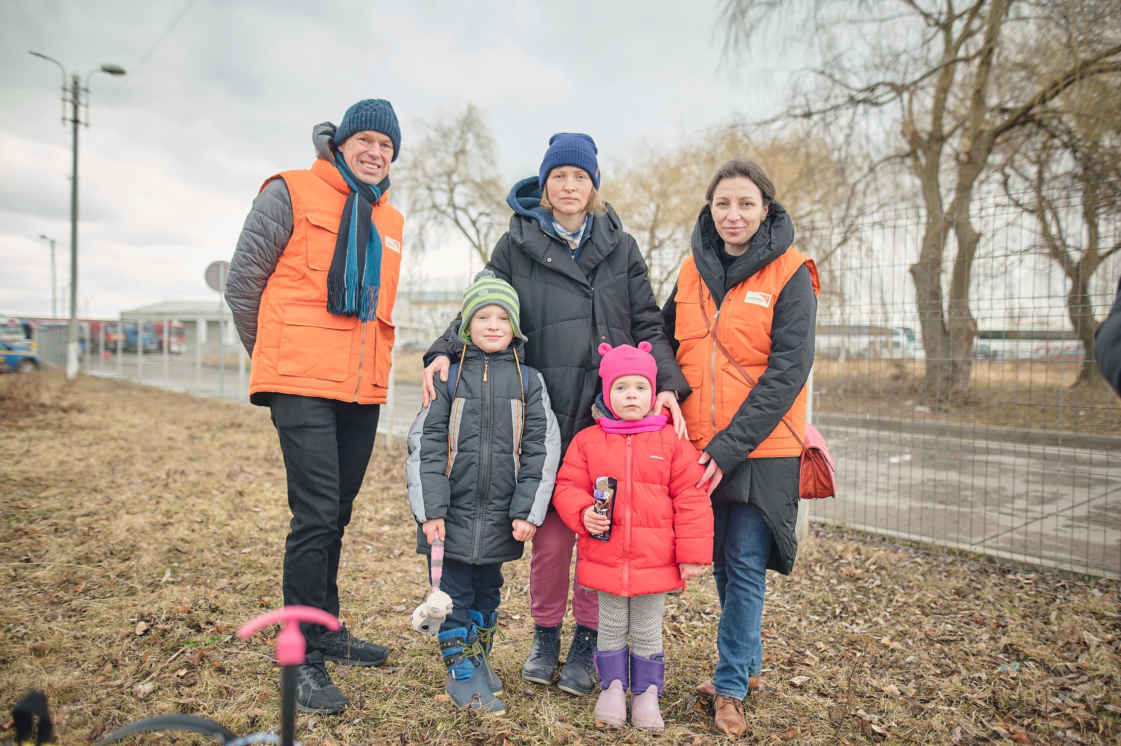 World Vision staff stand with a mother and children