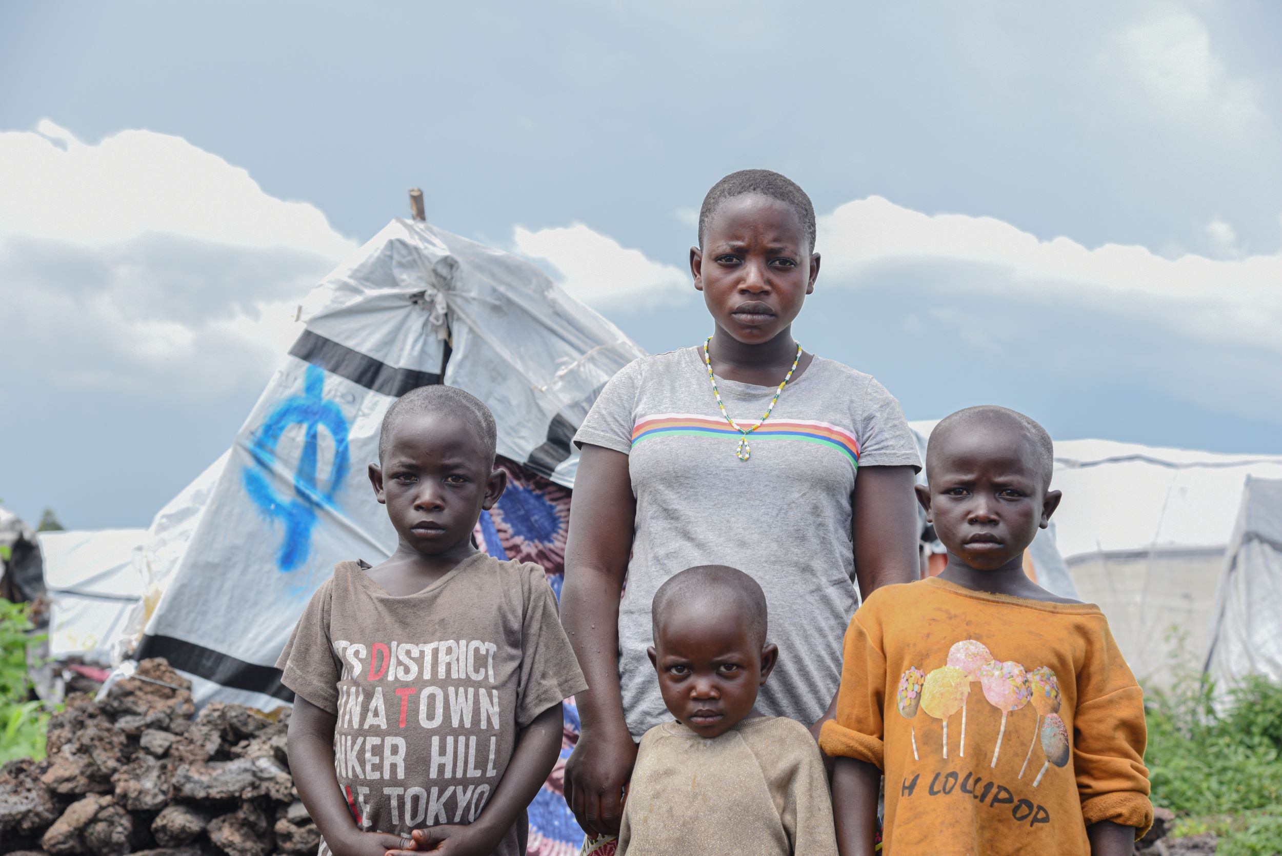 Four siblings standing before tents in a displacement camp in the Democratic Republic of Congo 