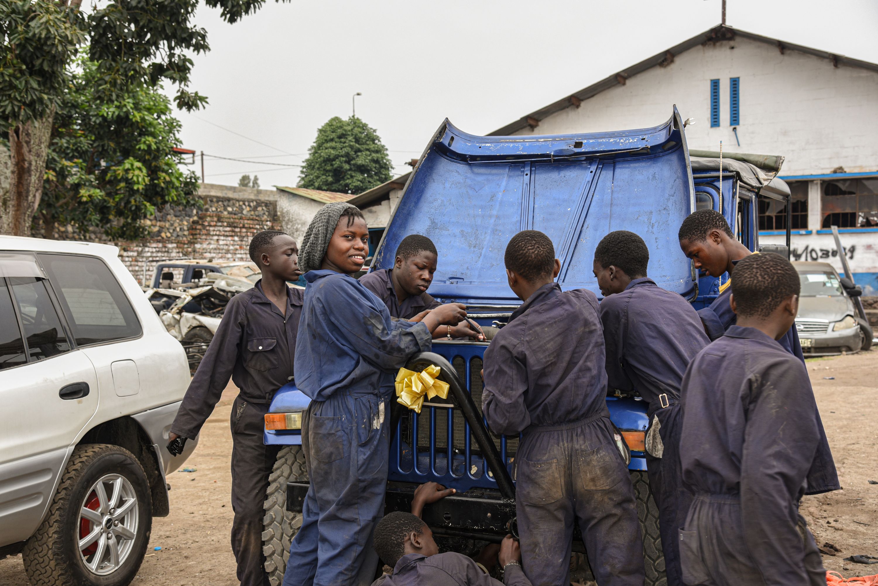 Immaculée works with a team of mechanics to fix a vehicle
