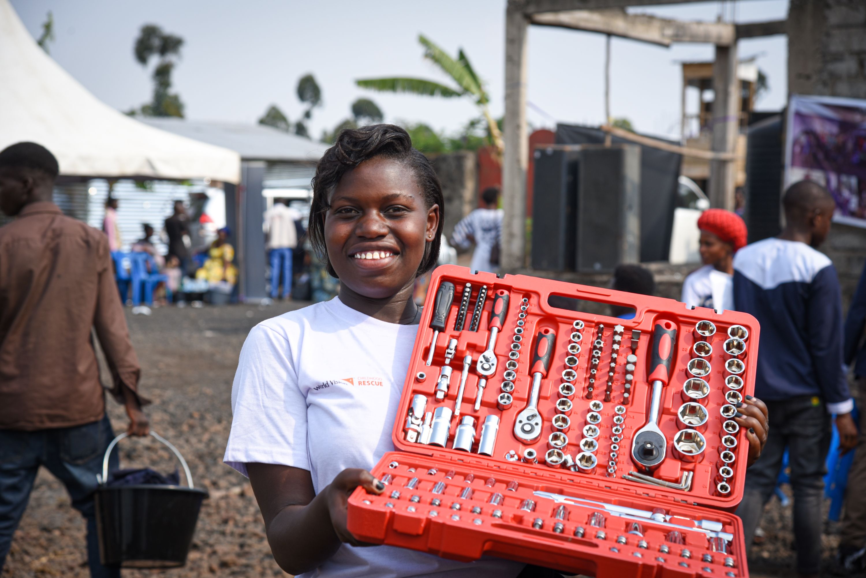 Immaculée smiles holding a set of tools,