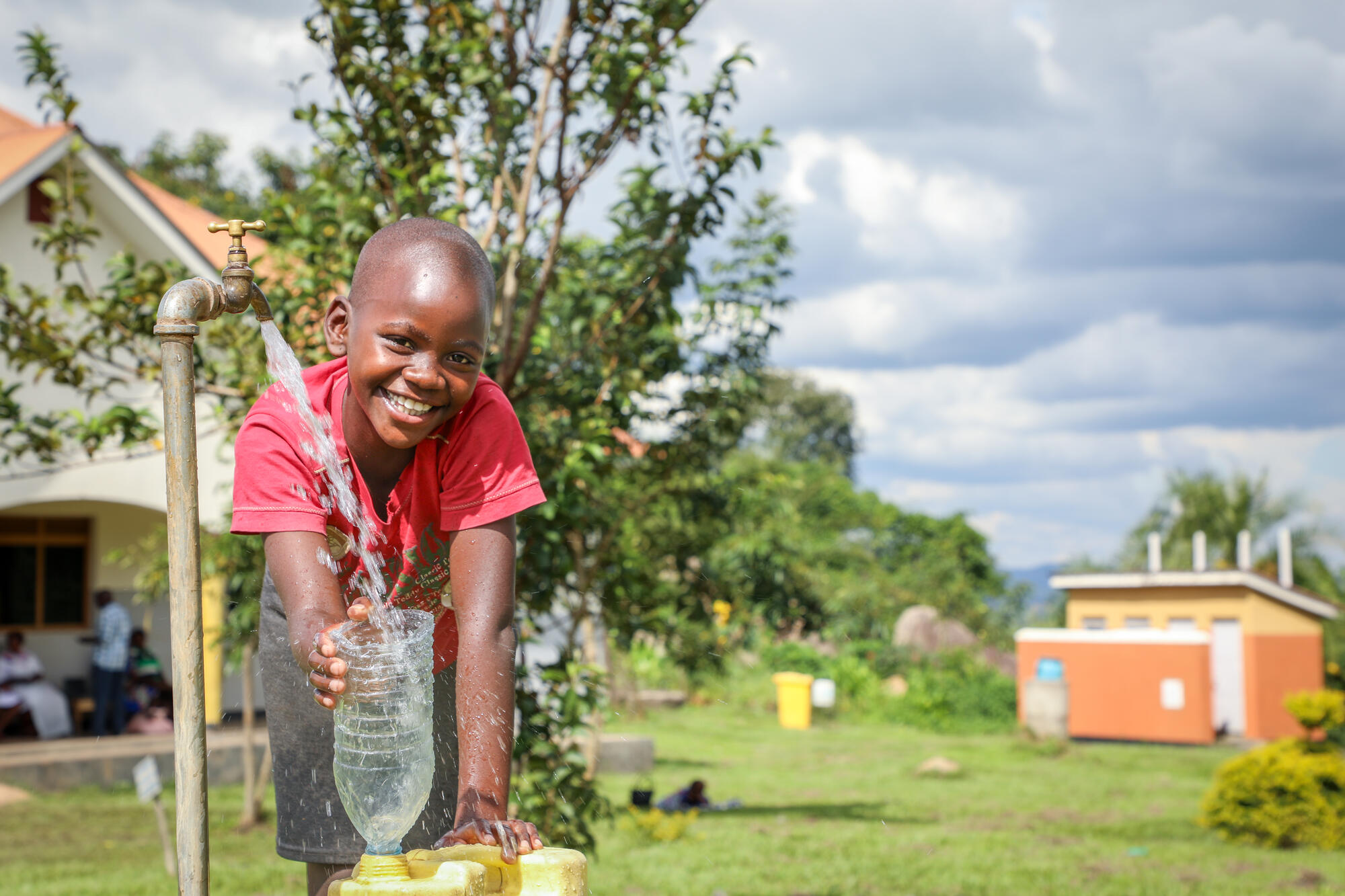 A young boy is filling a jerrycan with water running from a tap in a school yard in Uganda