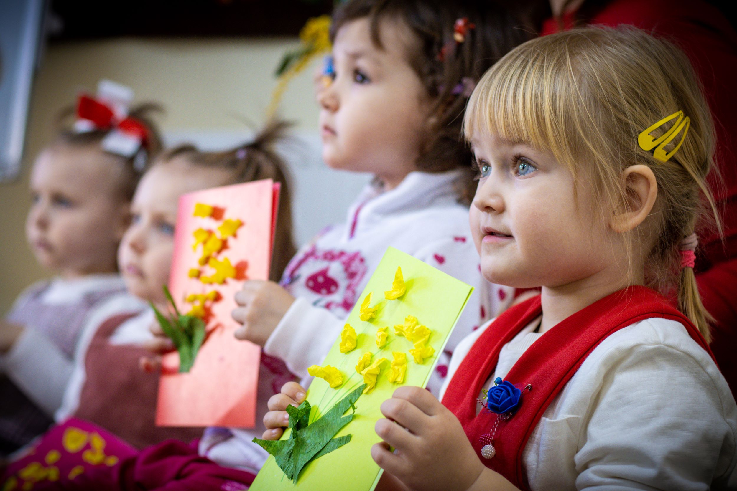Ukrainian girls holding up their colourful artwork at a Safe Zone in Moldova
