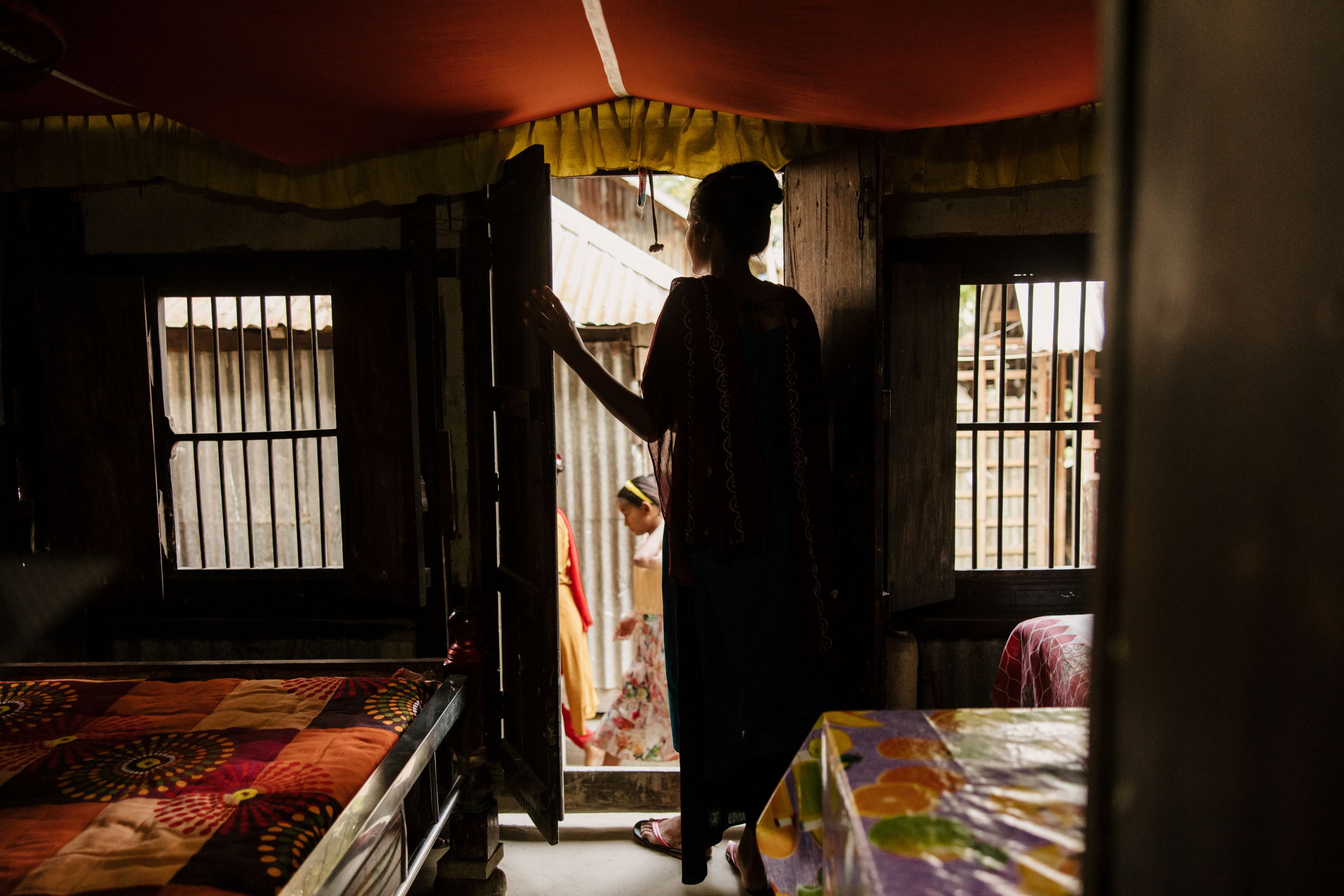 In a dark room, Farah opens the door to the bright outside world, mirroring her escape from child marriage 