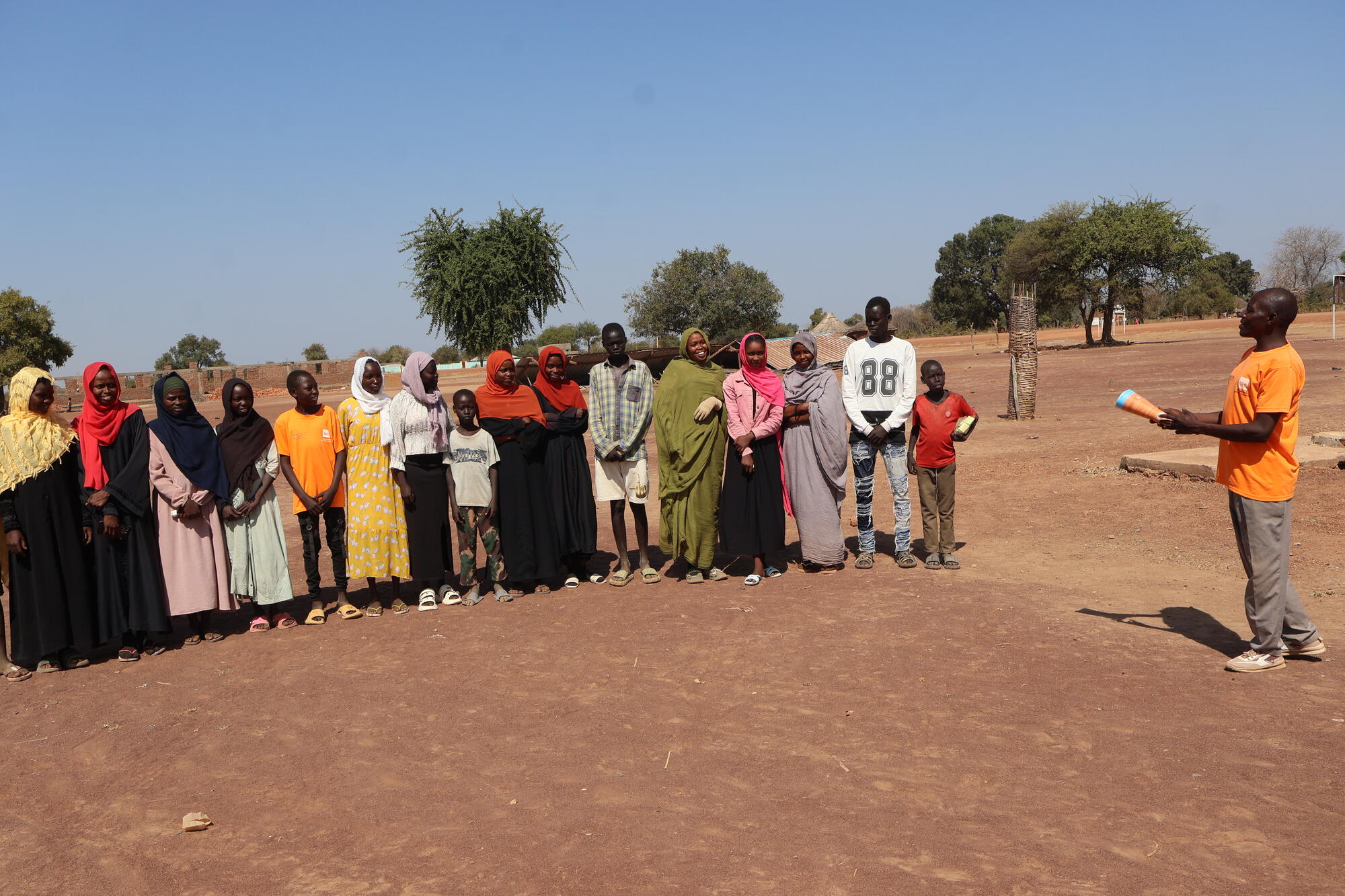 Isa stands outdoors with a group of school-age children in South Sudan.