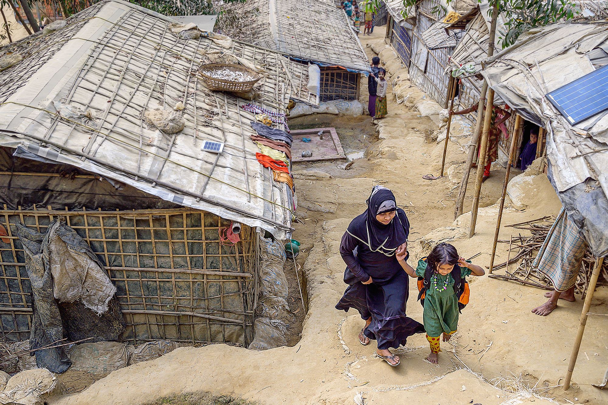 A child and their mother walking through the refugee camp.