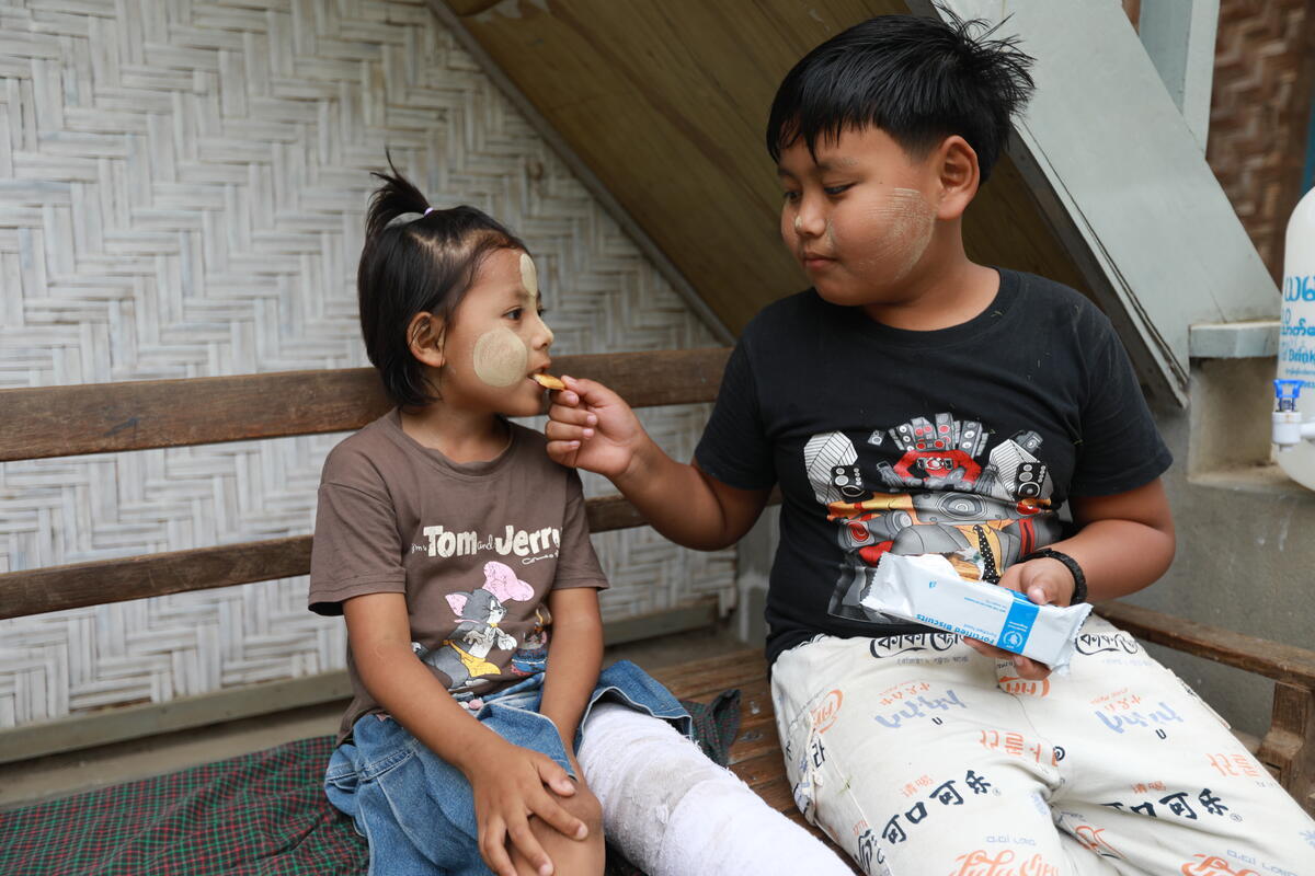 A young boy feeds his sibling