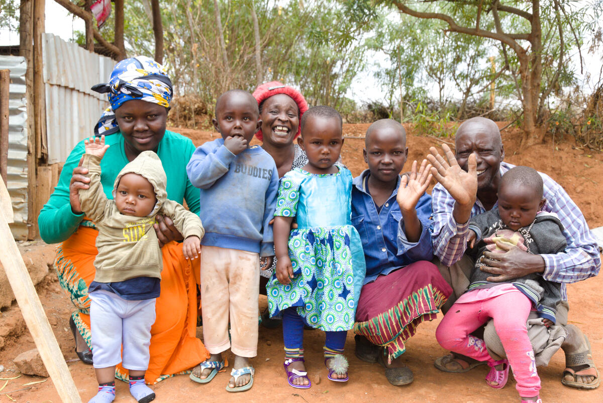 Victoria, her husband and their children pose together outside their home in Kenya.