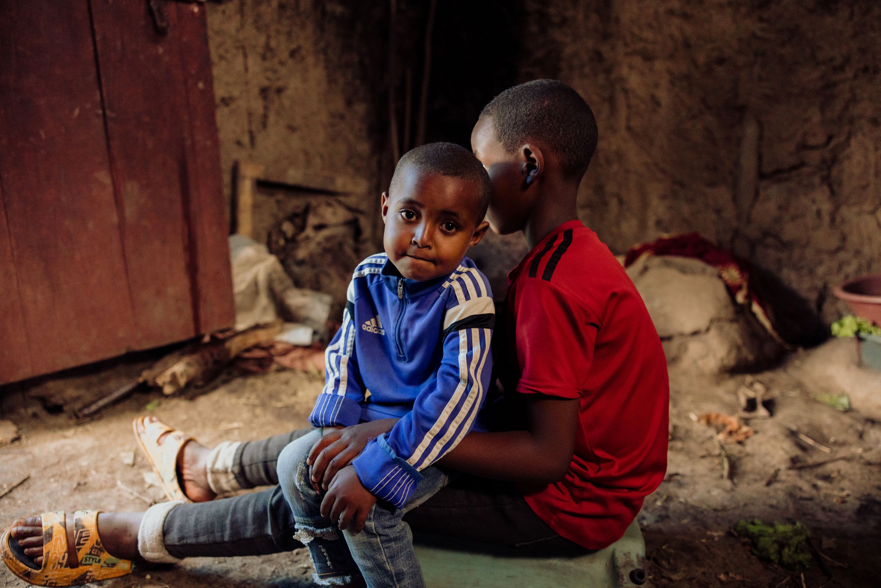 Dressed in blue, Nuredin, 3, sits on his big brother’s lap