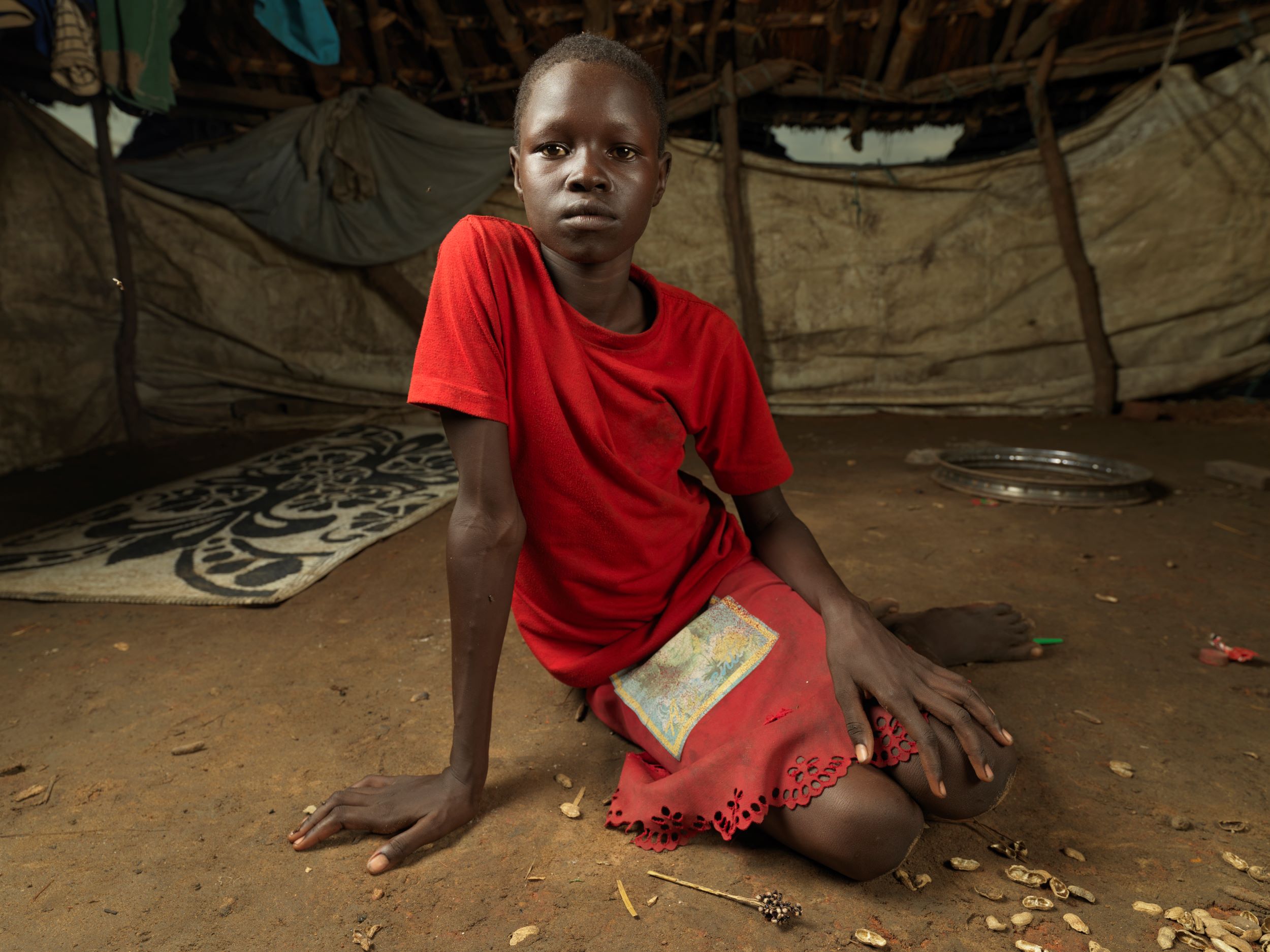 Orphaned girl, 10, sitting in her tent in a displacement camp, South Sudan 