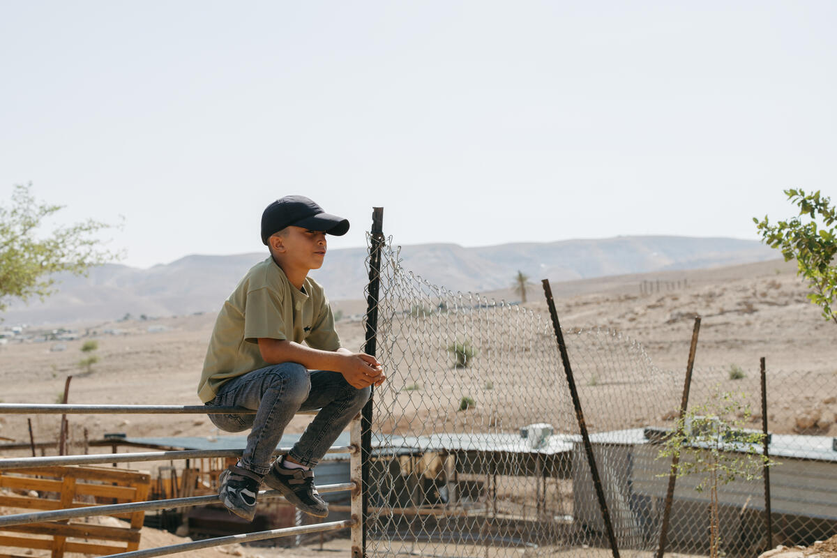 Child sat on a fence outside his home in the West Bank. 