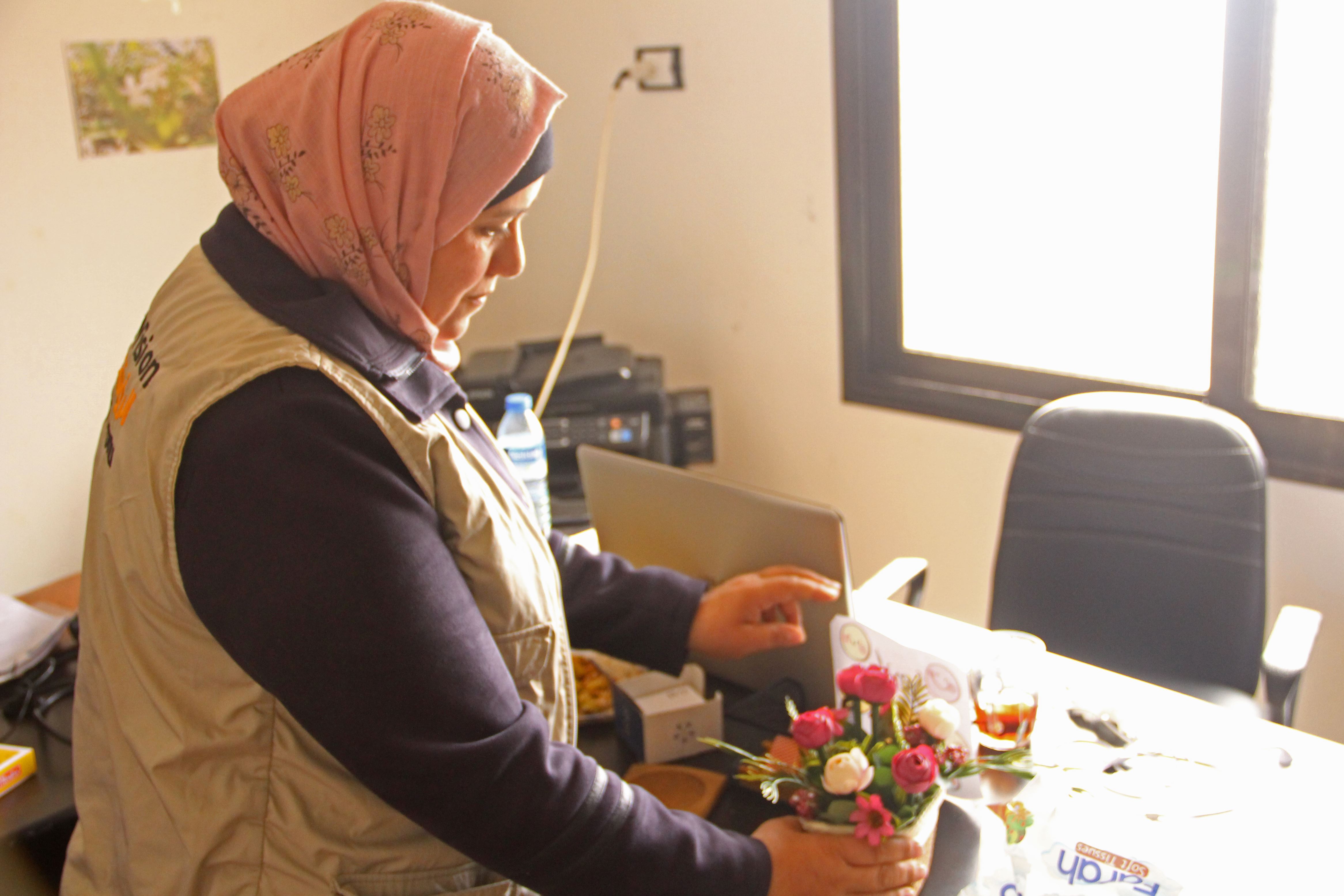 World Vision humanitarian worker places flowers on her desk in Syria where she trains other workers