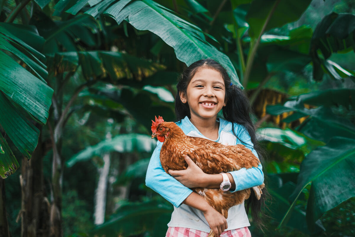 Young girl smiling and holding a chicken