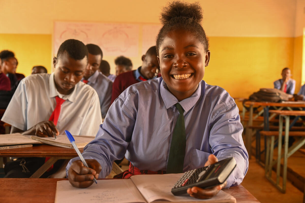 Child from Zambia sits at her school desk with pen in hand