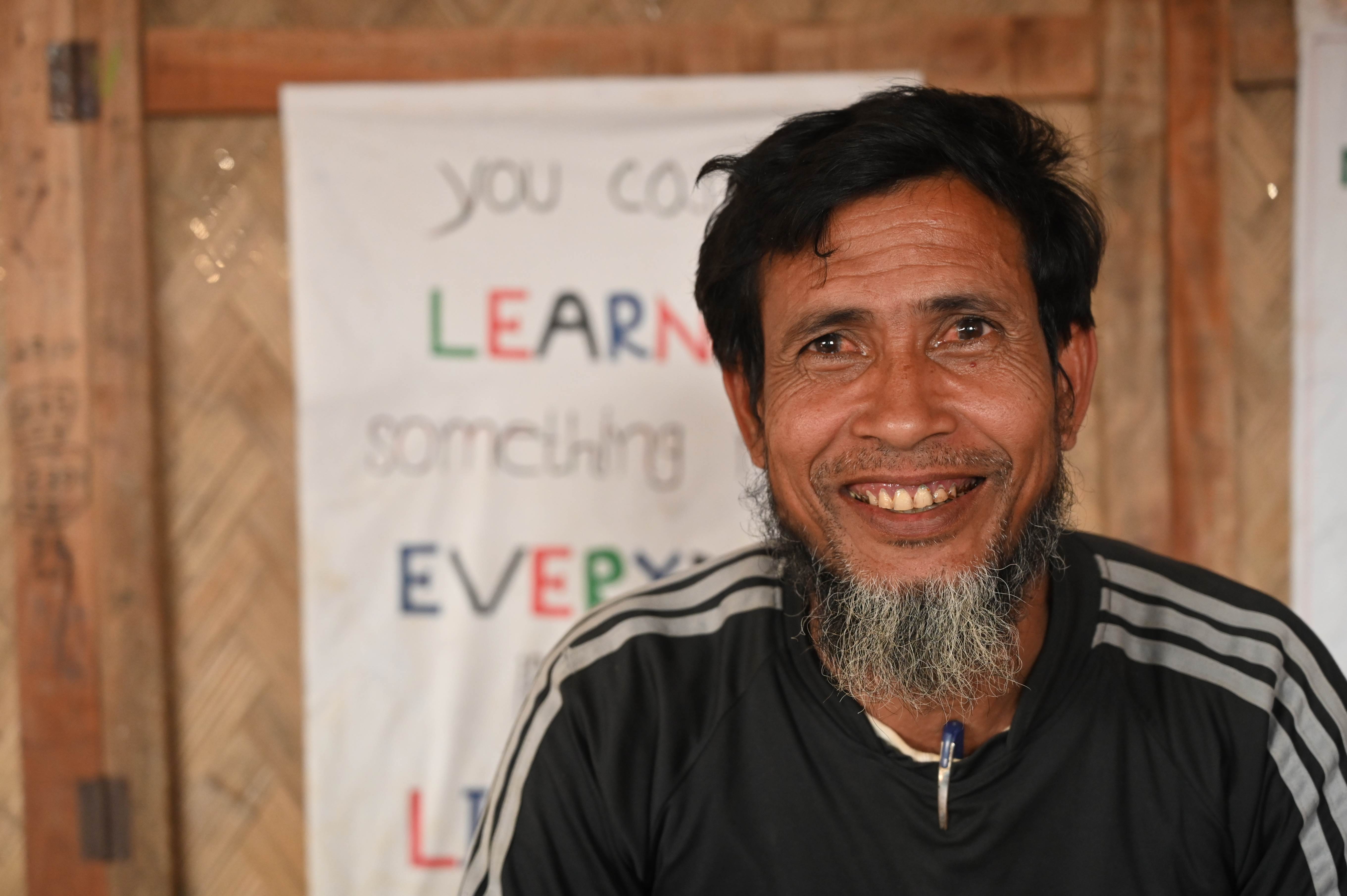Local leader smiles, sitting in a room in a refugee camp in Bangladesh