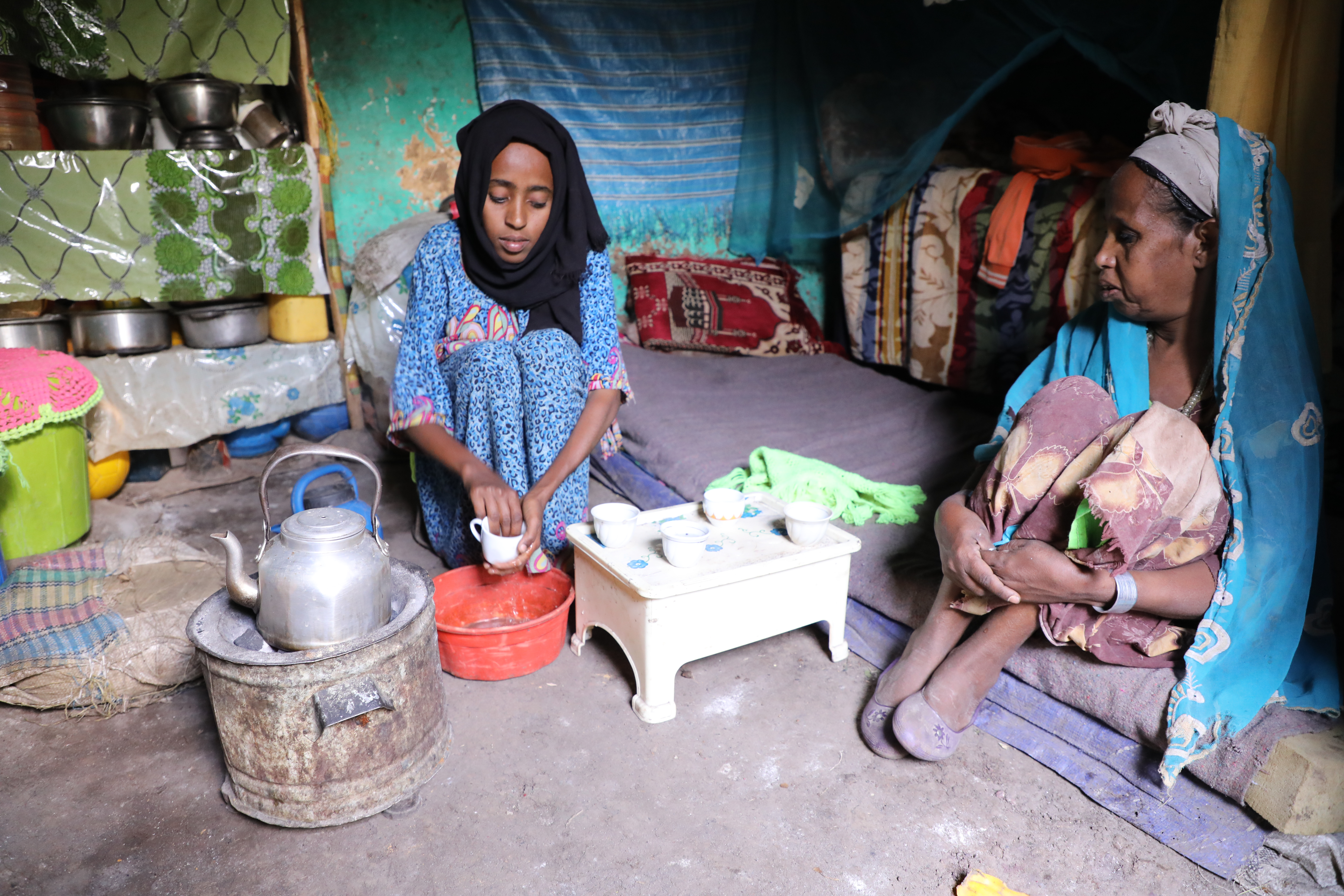 Merem, sits in the centre of a dirt-floor room, boiling water on a small stove, for coffee