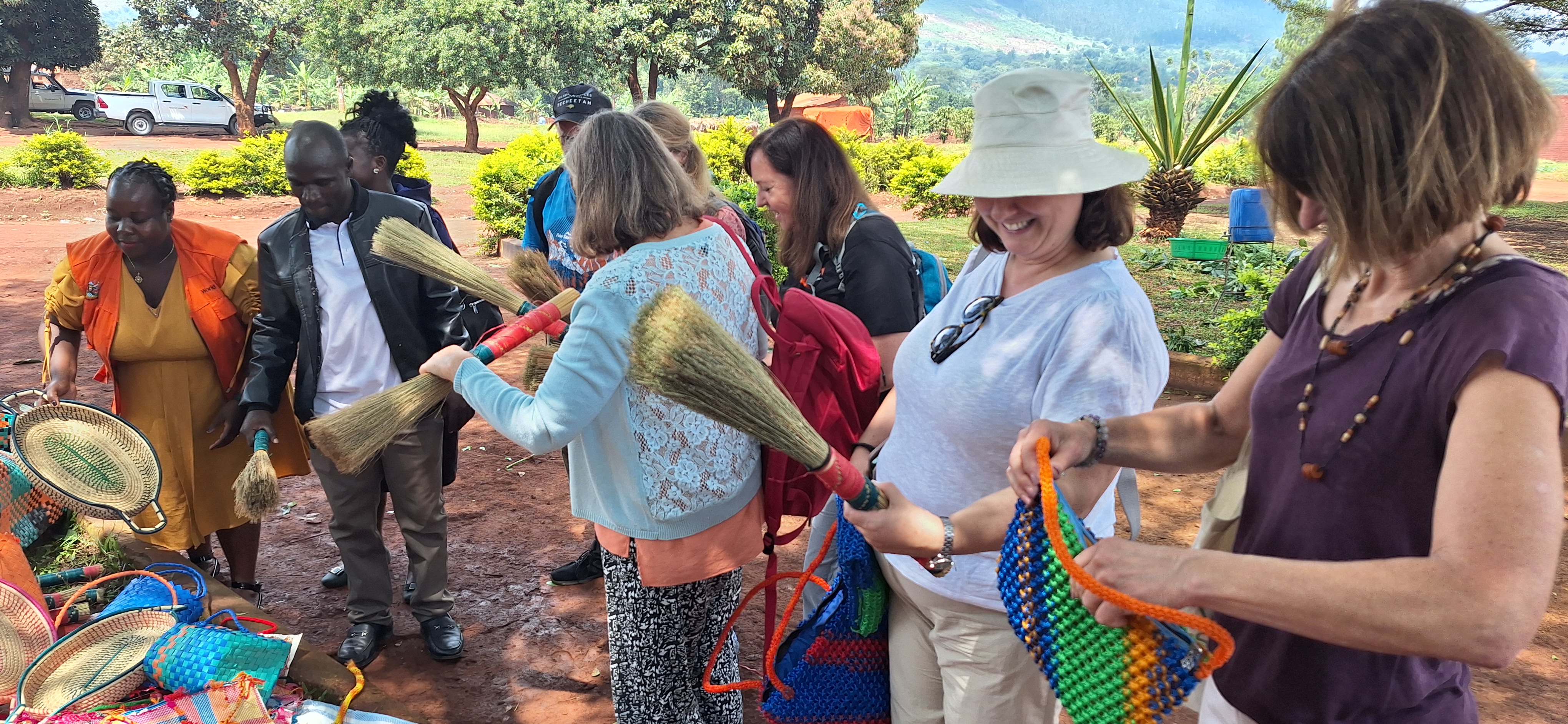 Emmanuelle and fellow visitors examine bags, broom sticks and baskets in delight having picked them up from a mat on the floor