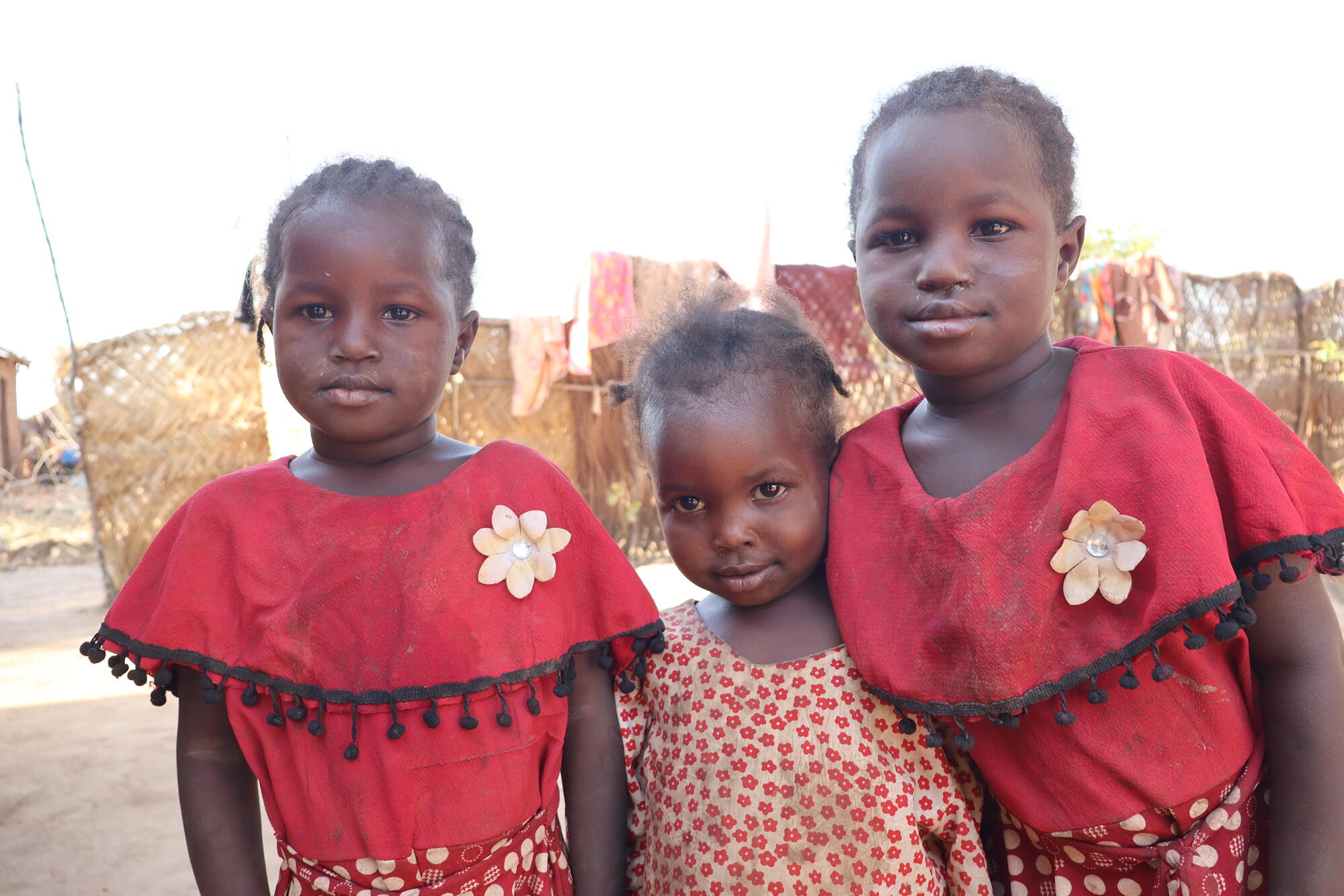 Three of Isa’s children stand together outdoors in South Sudan.