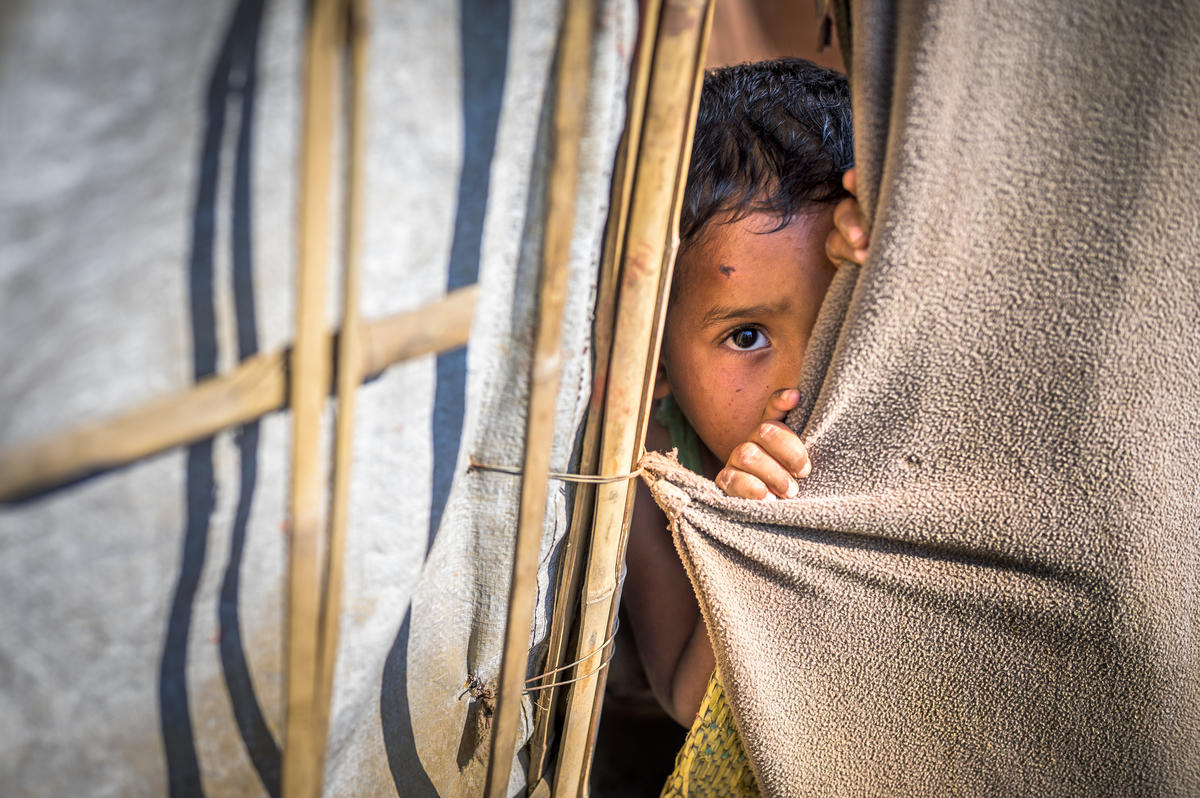 Child from Bangladesh peeking through a sheet