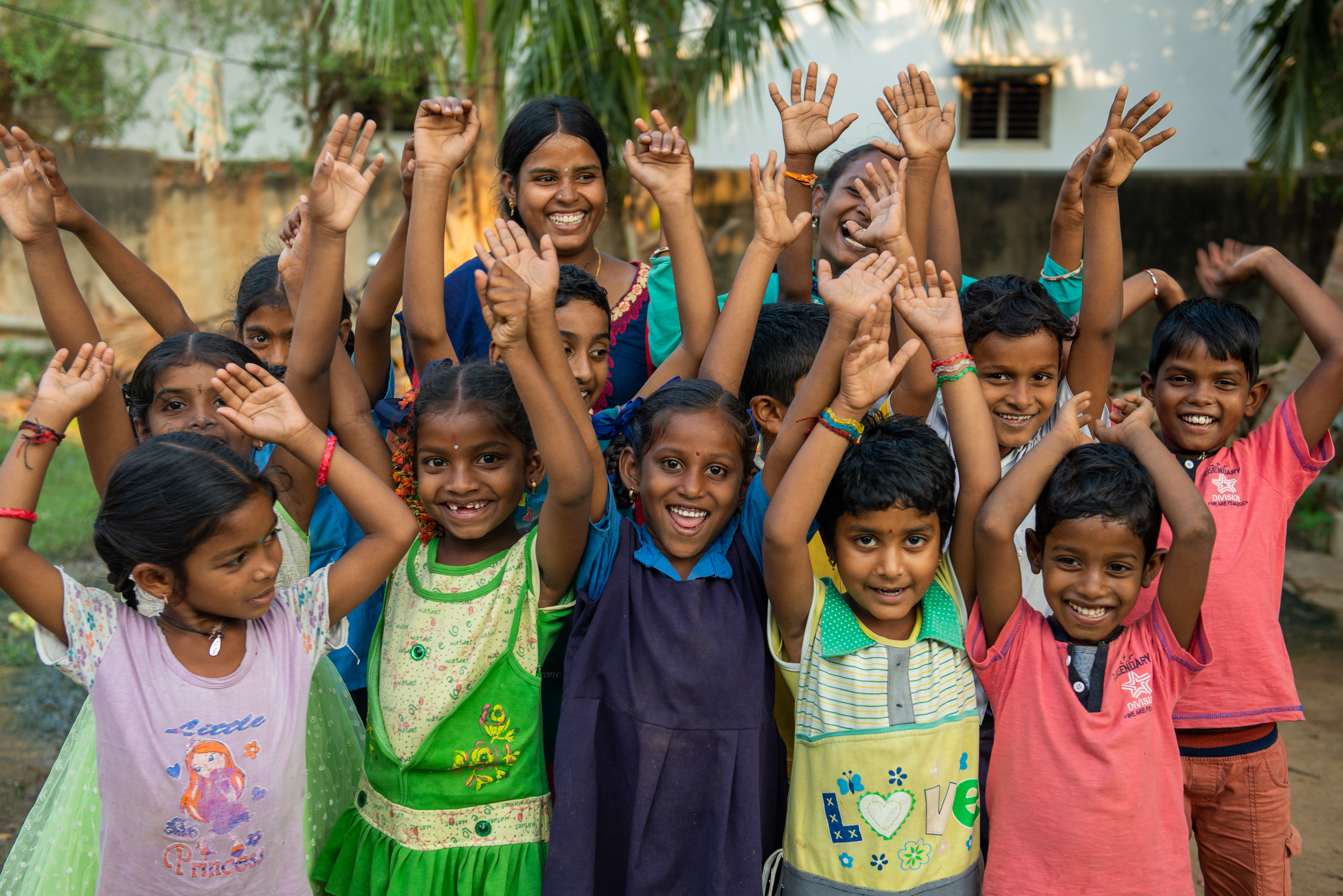 Anuradha smiles as her oldest sons and some of the children she helps at World Vision's Remedial Education Centre wave their hands in the air
