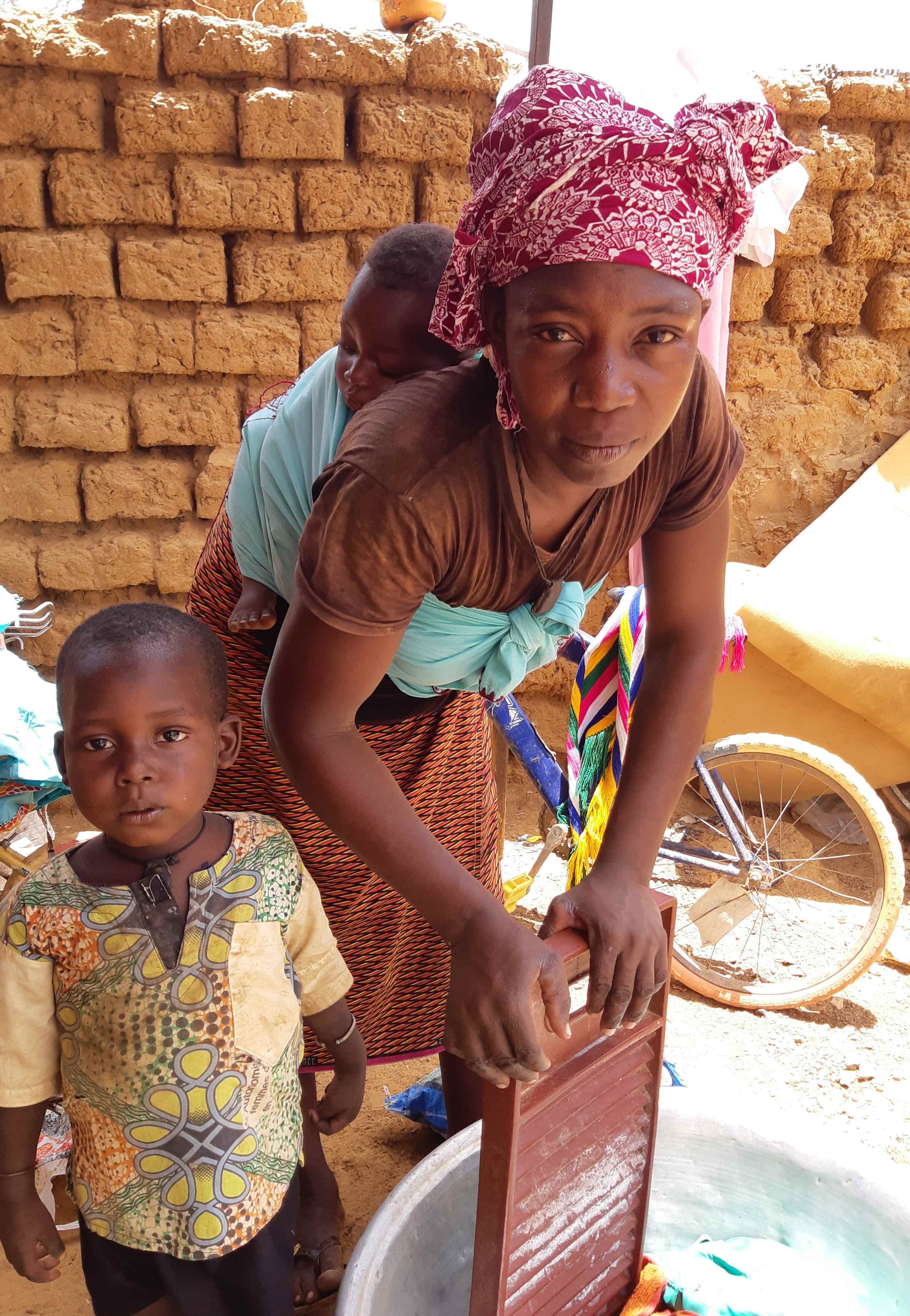 A mum in Mali prepares a meal with her baby on her back