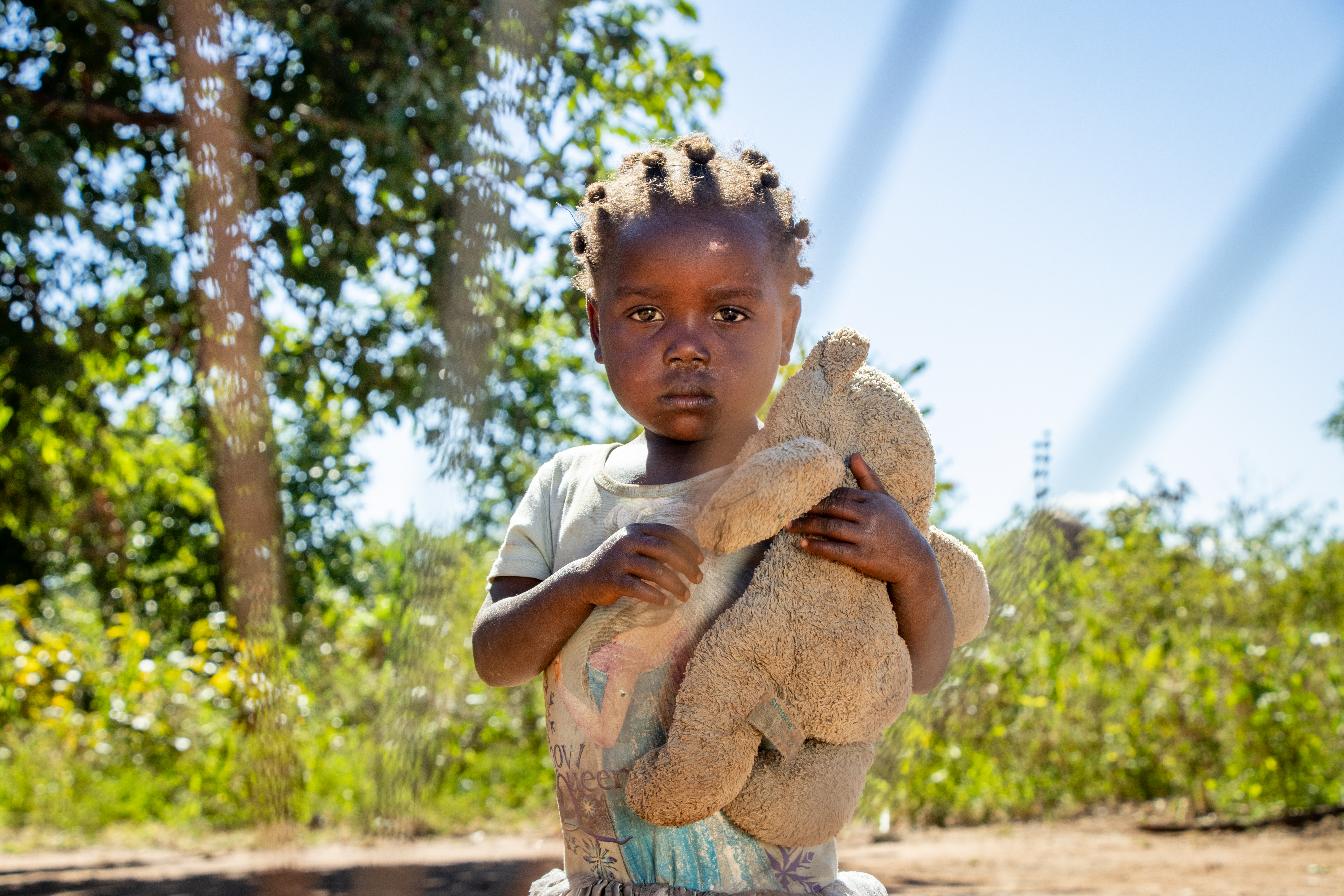 A little girl visiting a World Vision borehole in Nyimba District clutches a teddybear to her chest.