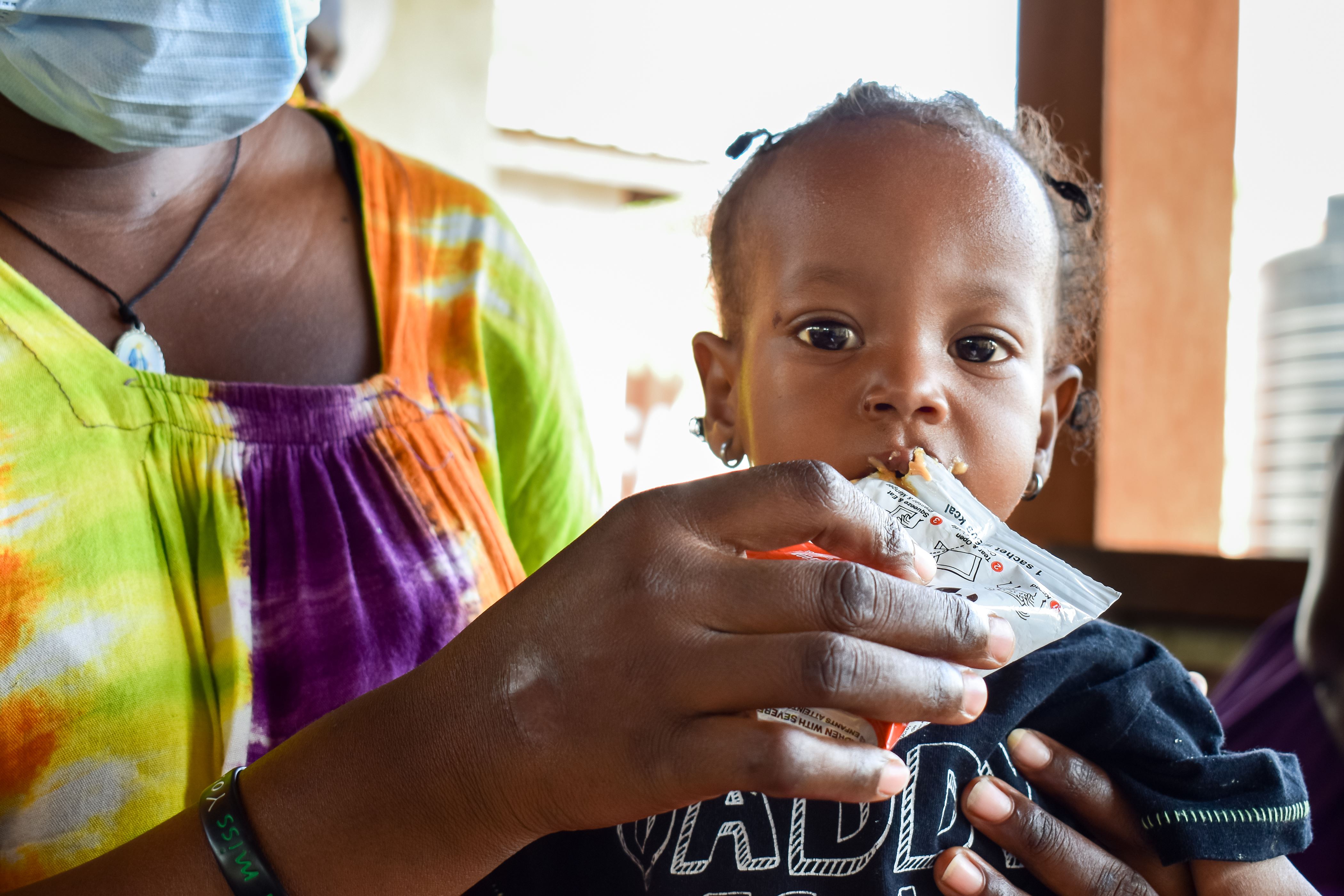 A young girl eats from a packet of specially fortified nutritious paste to combat malnutrition