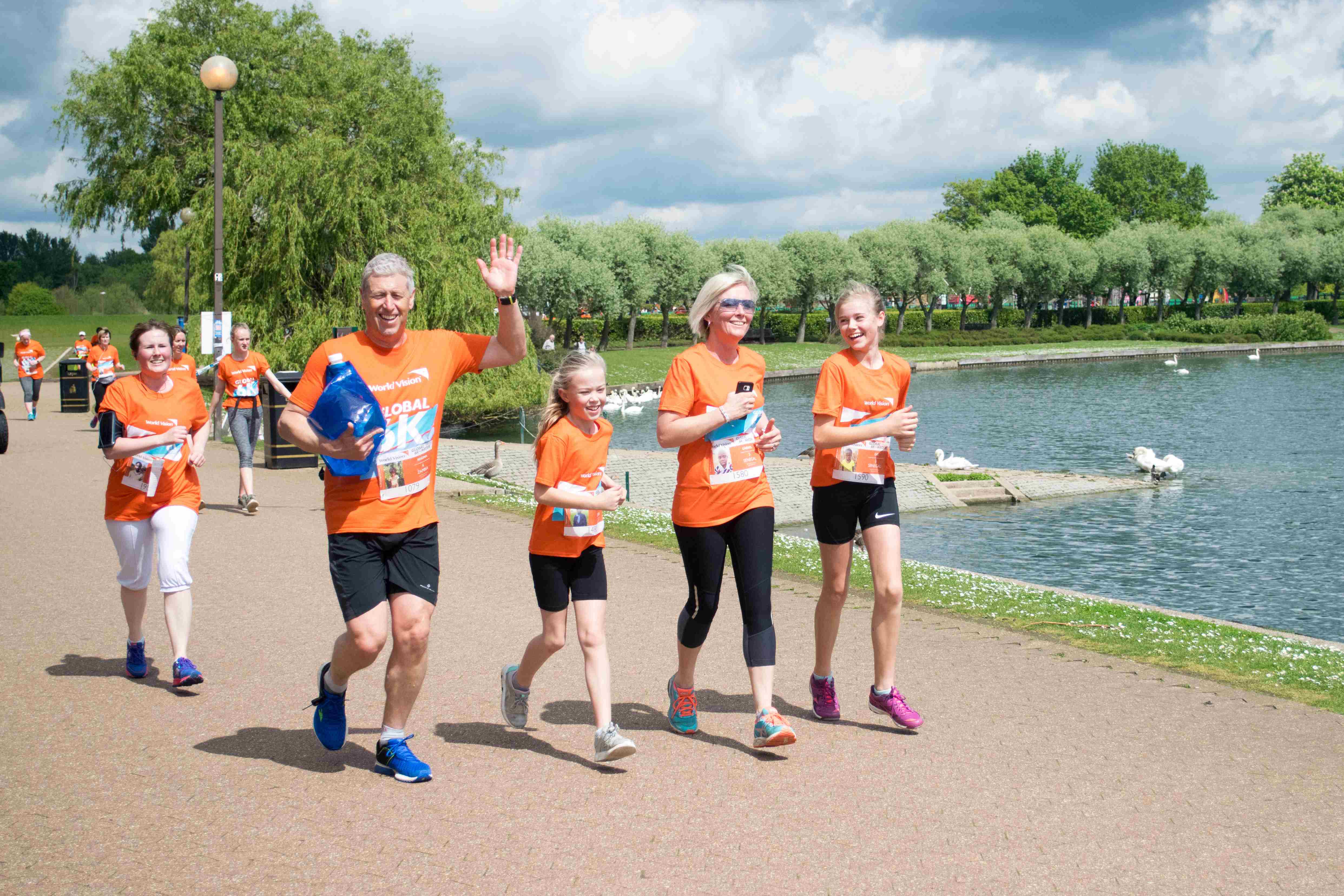 A family of four, two adults and two children, taking part in the Global 6K event, running past the lake.