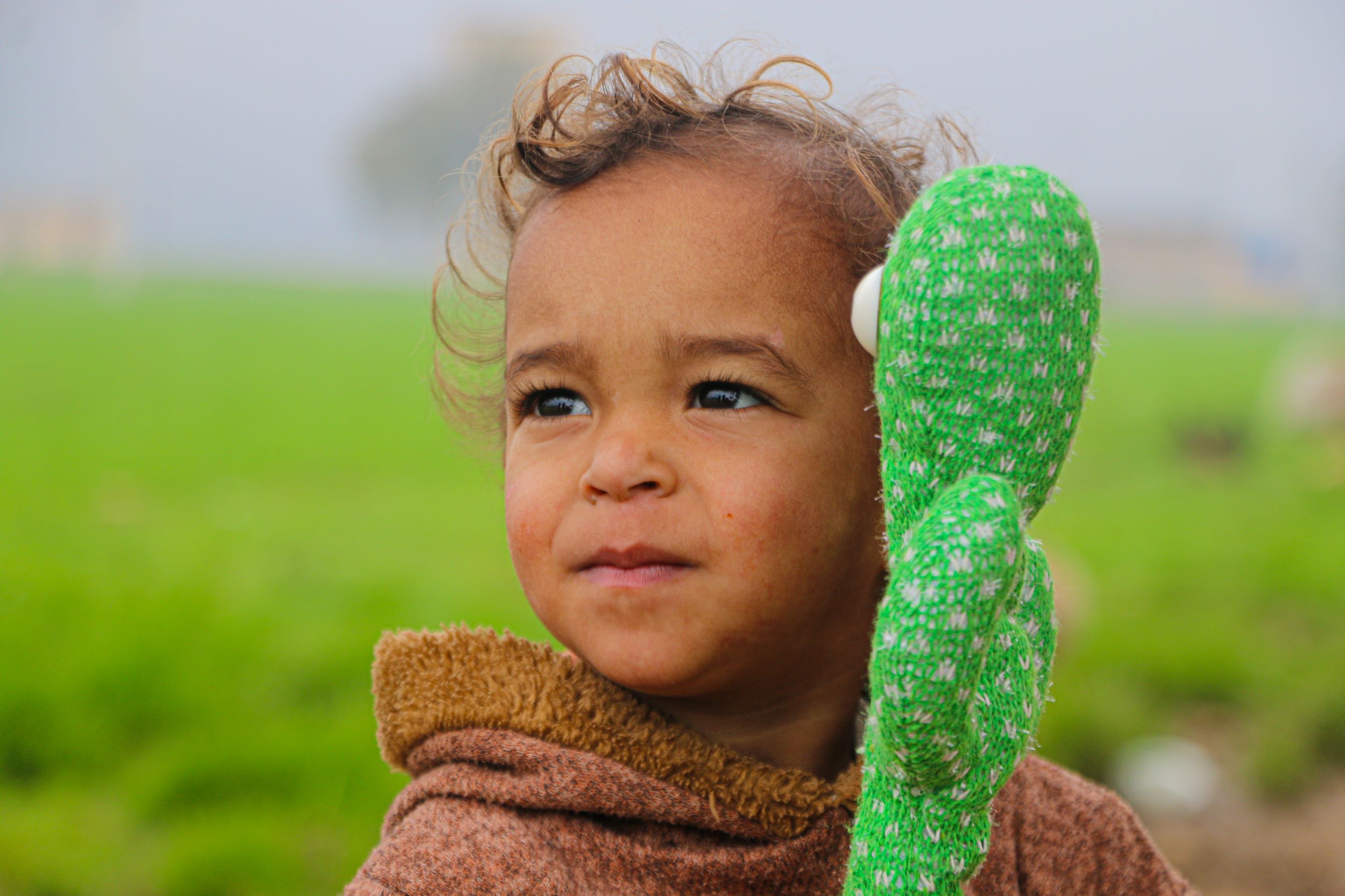  Smiling child standing in a green field holding her toy