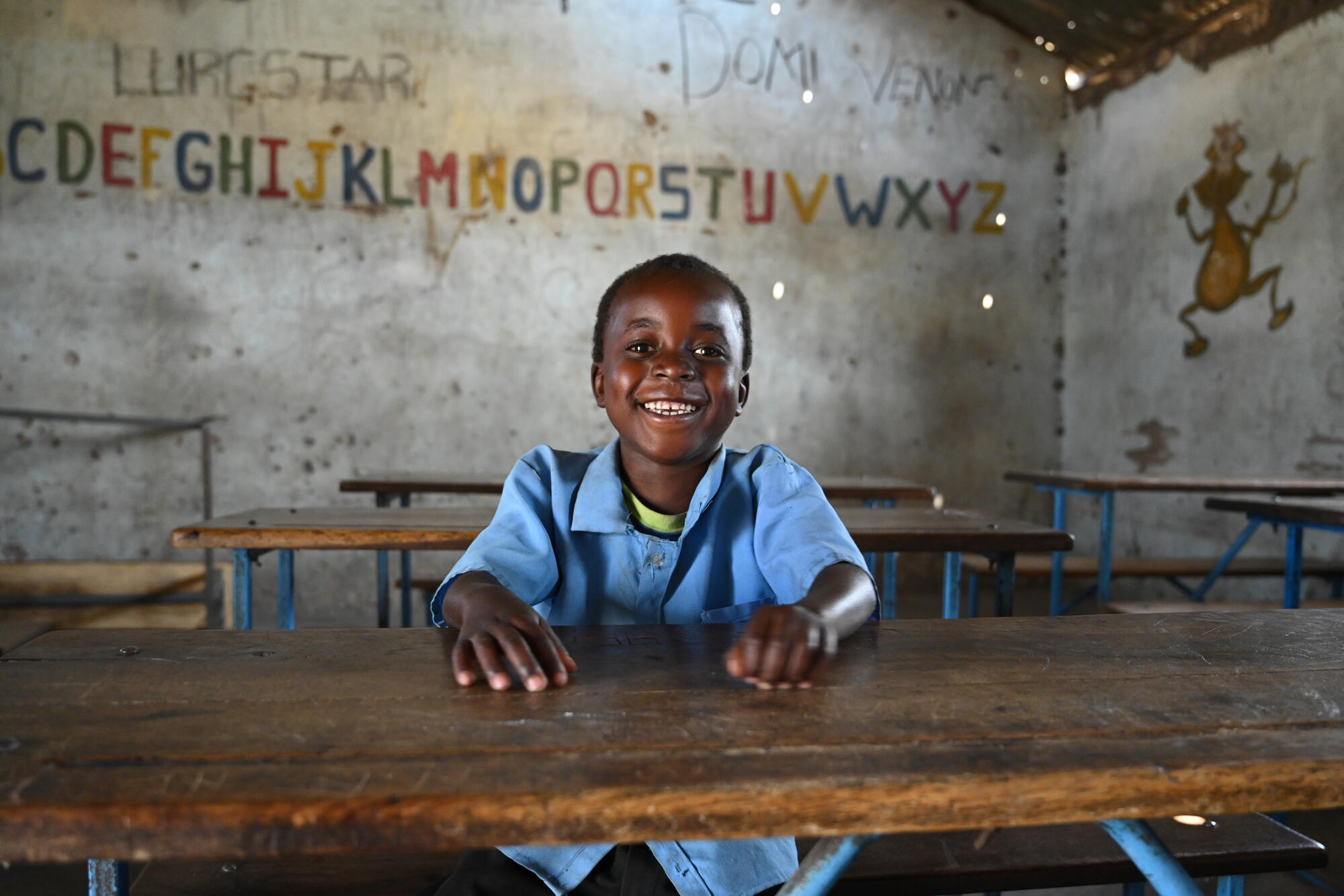 Schoolboy in Zamia sits as a desk smiling